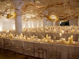 plenty of candles on each table and branches with lights make the space welcoming and cozy