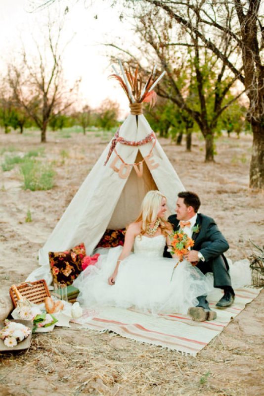 A romantic wedding picnic with a boho teepee, bright pillows, blooms, layered blankets for a boho loving couple