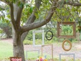 a vintage wedding picnic with a white blanket, with bright blooms, a basket and a vintage suitcase, a wedding cake and empty frames on the tree