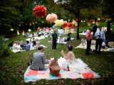 a bright wedding picnic with colorful layered blankets, bright paper pompoms and balloons and picnic baskets with food