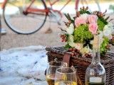 a wedding picnic with a basket, pastel blooms and greenery, apples, cheese, nuts and wine is perfect