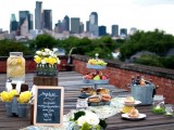 a rustic roof top wedding picnic with a reclaimed wooden table, bright blooms, fruits, lemonade, sweets and candles