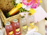 a low picnic table with food, refreshing drinks and a small basket with bright blooms inside