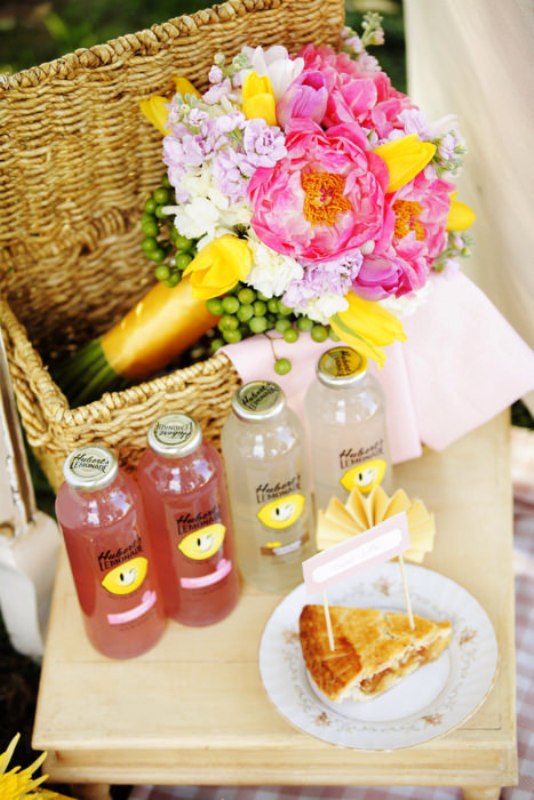 A low picnic table with food, refreshing drinks and a small basket with bright blooms inside