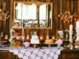 a vintage rustic dessert table made of rough wooden crates, with a doily tablecloth, candles and a vintage mirror in front of it