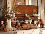 a rustic vintage dessert table of wine barrels, a tabletop with lots of books, dried and fresh bloom arrangements and a wooden box with sweets