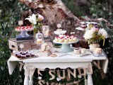 a vintage white table with a gold letter garland, neutral blooms and crates and suitcases as sweets stands