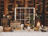 a rustic vintage dessert table with crates as sweets stands, a window, a jar with lights and some blooms in a vase is a cool idea
