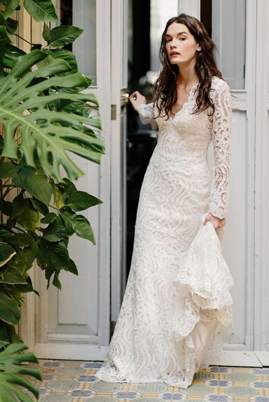 A romantic fitting boho lace wedding dress with a deep neckline, long sleeves and a train