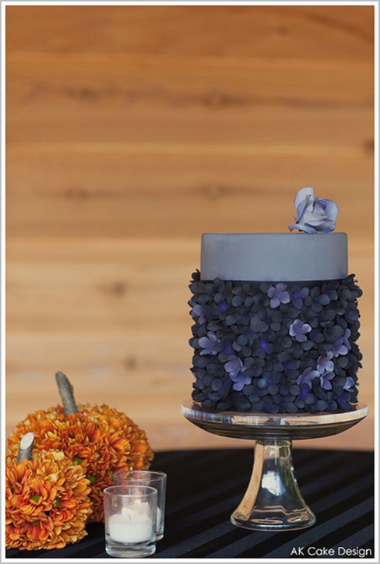 An eye catchy dark wedding cake with a sleek top tier and a dark flower lower tier plus a bloom on top is a lovely idea for a modern dark wedding