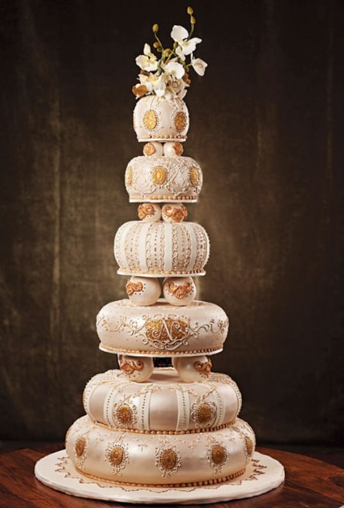 a white wedding cake with gold patterns, with semi spheres and small spheres is a great idea for a whimsical wedding with a vintage feel