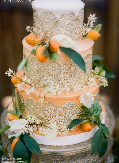 an ombre orange wedding cake with three tiers decorated with gold lace, with succulents, white blooms and kumquats is a lovely idea