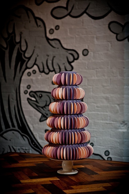 A purple wedding cake decorated with colorful semi circle sugar pieces is an eye catchy and bright idea for a wedding