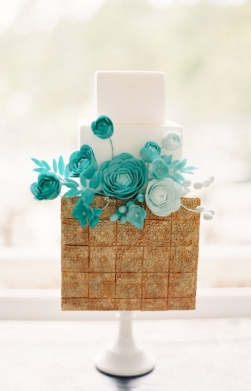 a square wedding cake with white tiers and a solid tier clad with cookies plus ombre white to teal sugar blooms for a catchy and contrasting wedding