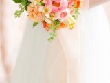 a colorful summer wedding bouquet made of pink and blush peonies, orange and yellow blooms and greenery is fun and bold