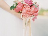 a bright pink peony wedding bouquet with greenery and baby’s breath and long neutral ribbons for a spring or summer wedding