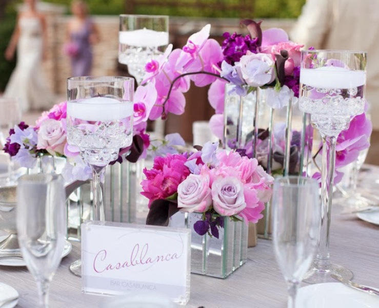 A bright radiant orchid and pink wedding centerpiece with candles and mirror vases is amazing