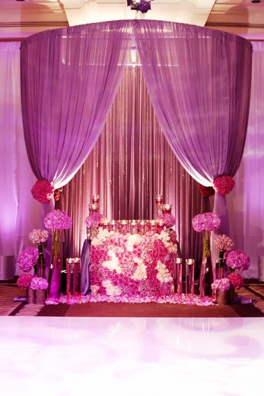 A radiant orchid wedding altar with blooms, candles, radiant orchid curtains and blooms plus lights