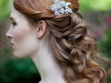 a vintage half updo with waves and curls, twists on top and a shiny rhinetone hairpiece