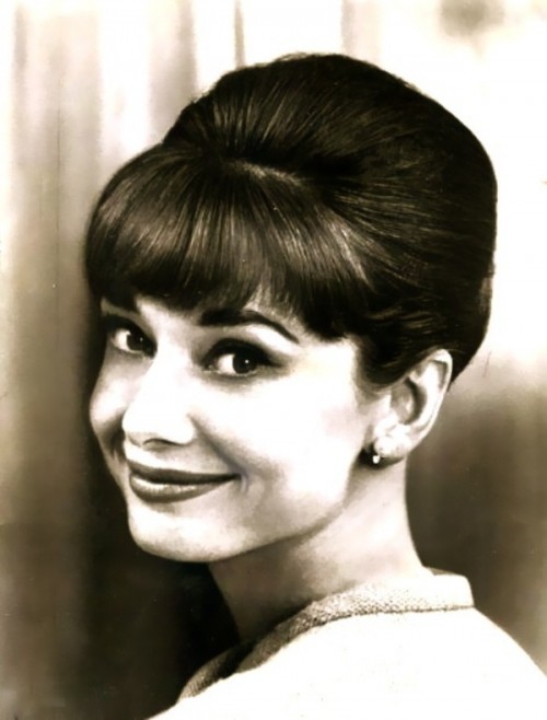 a classic Audrey Hepburn hairstyle - an updo with a volume on top and a fringe, all sleek and elegant