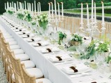 lush greenery and white bloom centerpieces and tall thin candles highlight the length of the tables