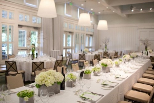 a neutral tablescape with white blooms and greneery, with glasses and green menus