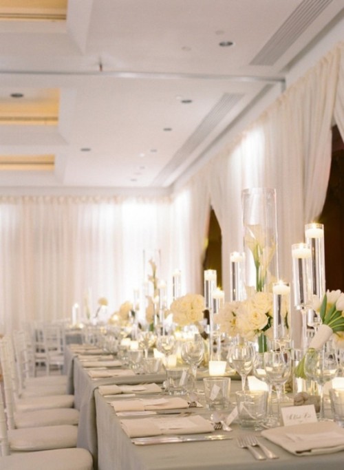 a pure white and ivory formal table setting with candles, floating and usual ones and blooms
