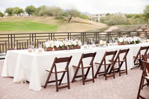 dark stained chairs and plywood planters contrast the white blooms and tablecloths
