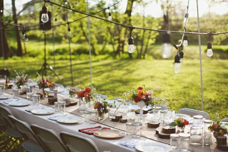A white tablecloth, a burlap runner, wood slices and white candles plus colorful floral centerpieces