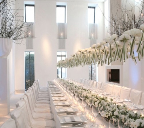 white bloom centerpieces and an overhead decoration visually elongate the tables evne more
