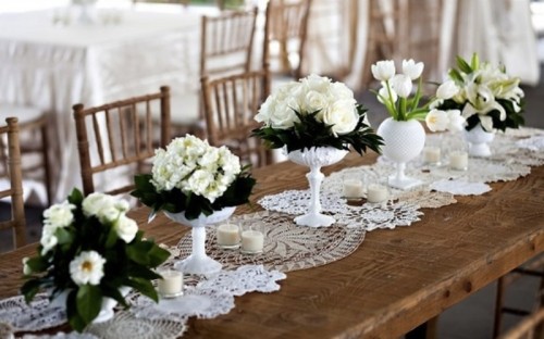 a neutral doily table runner paired with lush white floral centerpieces for a vintage chic feel at the table