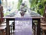 a purple lace wedding table runner highlights the purple floral centerpieces in vintage silver teapots