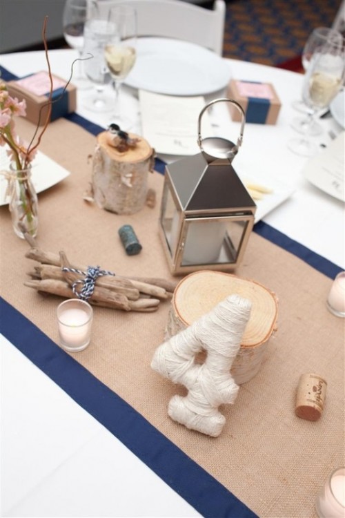 a burlap and navy table runner over a white table for a nautical or coastal wedding