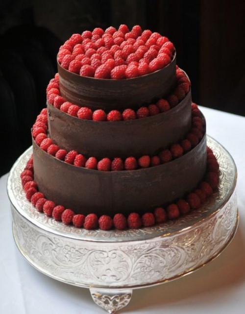 a chocolate wedding cake with raspberries all over it is a delicious and gorgeous-looking dessert for a wedding, it's amazing