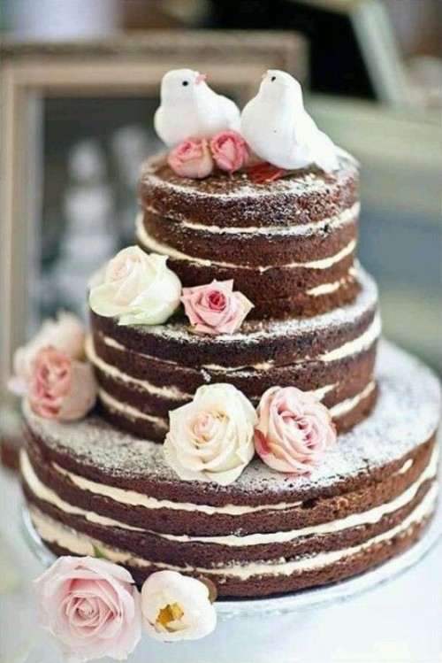 a chocolate naked wedding cake with white and pink blooms and white pigeon cake toppers is a lovely and delicious-looking idea