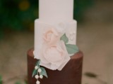 an elegant white and chocolate buttercream wedding cake with pink faux blooms, berries and greenery is a gorgeous idea to rock at a refined wedding