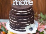 a naked chocolate wedding cake with a white anemone and a white letter cake topper is a stylish and bold idea for a modern wedding