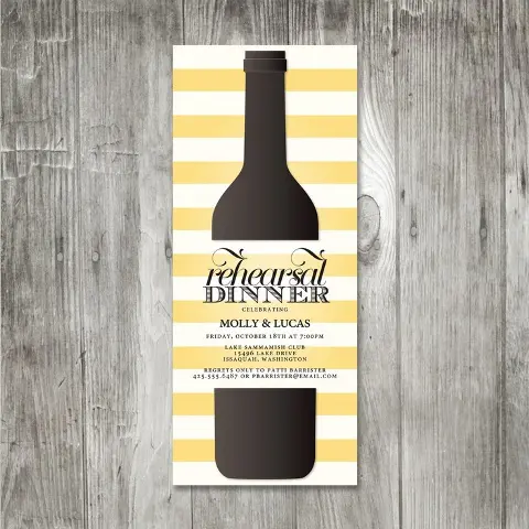a colorful yellow and white striped rehearsal dinner invitation with a bottle printed for a vineyard rehearsal
