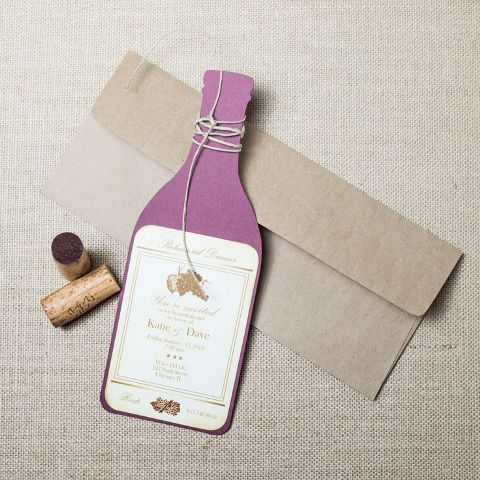 a stylish rehearsal dinner invitation styled as a purple wine bottle in a kraft paper envelope is a cool idea for a vineyard rehearsal