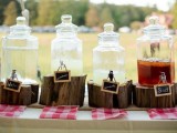 a rustic drink station with glass tanks placed on wood slices and with framed chalkboard markers