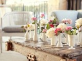a rustic pallet coffee table with colorful blooms in white vases
