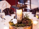 a wood slice with moss, pincones, cotton and a modern metal candle lantern
