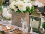 candle lanterns, a plywood planter with lush neutral blooms, sheer chargers and silver cutlery