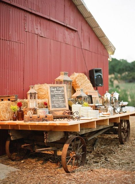 a table on wheels with hay, candle lanterns and chalkboard signs can be used to serve anything