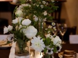 a lush white floral centerpiece in jars decorated with burlap and lace