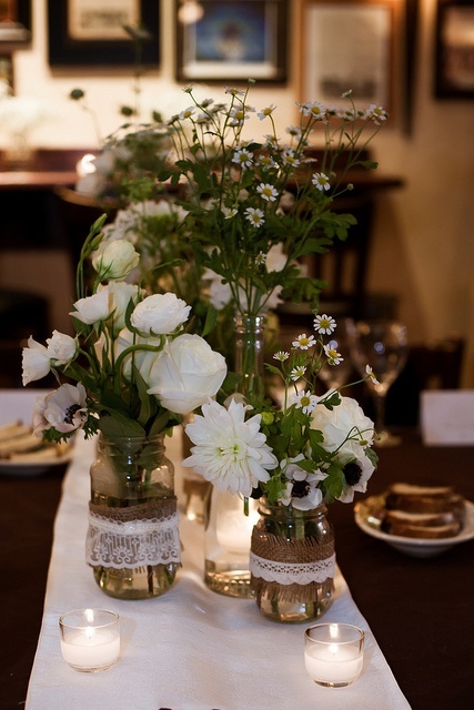 a lush white floral centerpiece in jars decorated with burlap and lace