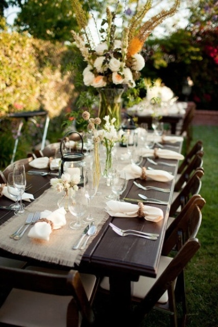 a rustic tablescape with white and yellow blooms and a burlap runner