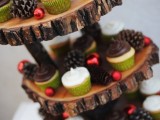 a cool woodland wedding sweets stand of wood slices, with pinecones and mini red Christmas ornaments is ideal for a rustic holiday wedding