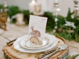 a mountain and woodland wedding tablescape with en evergreen table runner, wood slices, deer cards and candles