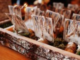 a wedding seating chart done of a bark box with moss, wood pieces and birch bark cards